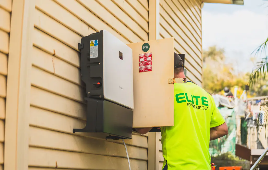 Electrician installing a solar inverter and battery system